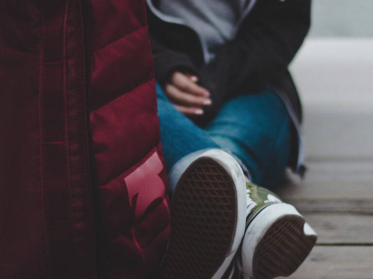 Person sitting on street with bag
