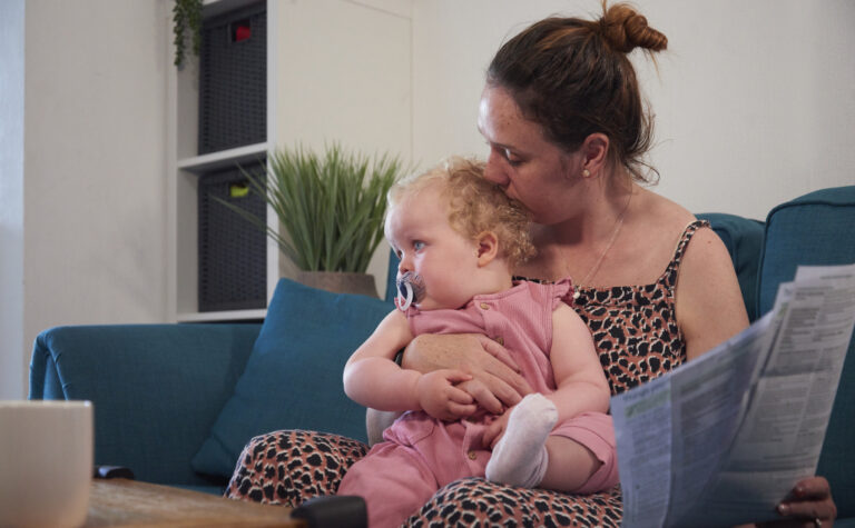 A mother sat with her young daughter on the couch looking through paperwork
